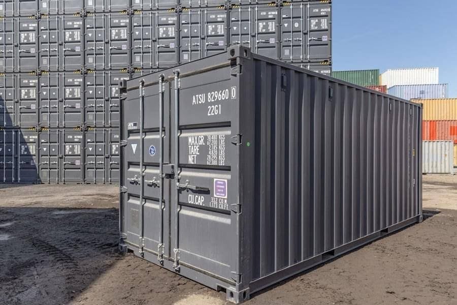 Refurbished shipping containers repainted in a uniform grey standing in a yard