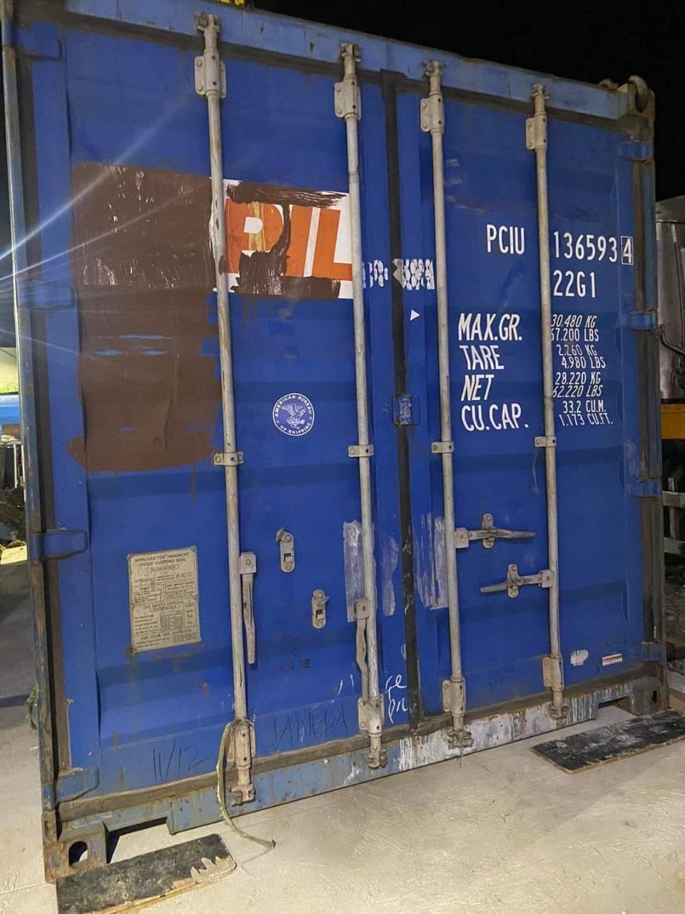 Close-up of the door end of a used container showing lock rods, cams and markings