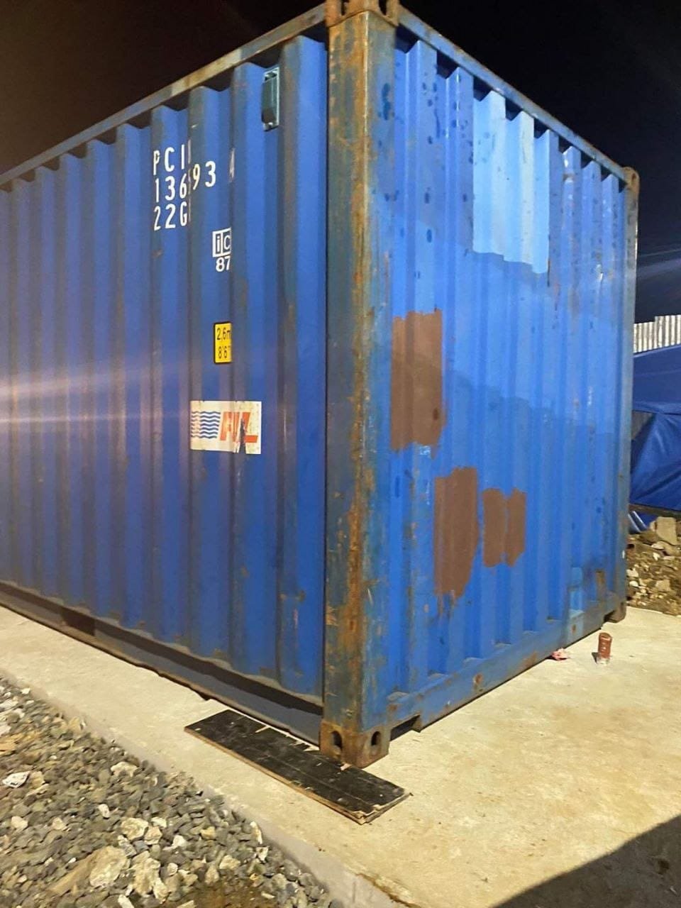Used blue shipping container showing patches of surface corrosion on the side panel